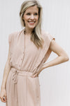 Close up of button bodice and elastic waist on a beige jumpsuit with cap sleeves. 