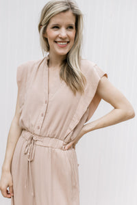 Close up of button bodice and elastic waist on a beige jumpsuit with cap sleeves. 