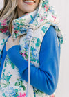 Close up of the rope tie from the hood of a white vest with a pink, blue and green floral pattern 