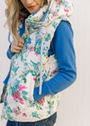 Model wearing a white puffer vest with blue, pink and green floral design, hoodie and pockets.