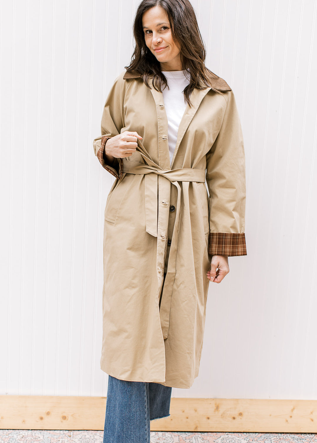 Model wearing a camel colored trench coat with button front, tie waist and long sleeves. 