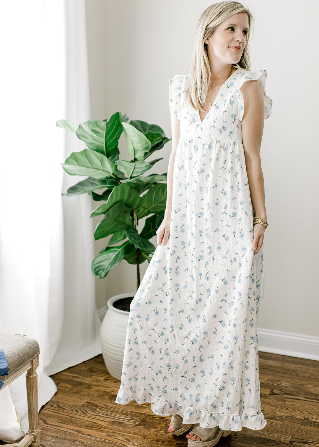 Model wearing a textured cream maxi with pale blue floral, v-neck and flutter cap sleeves.