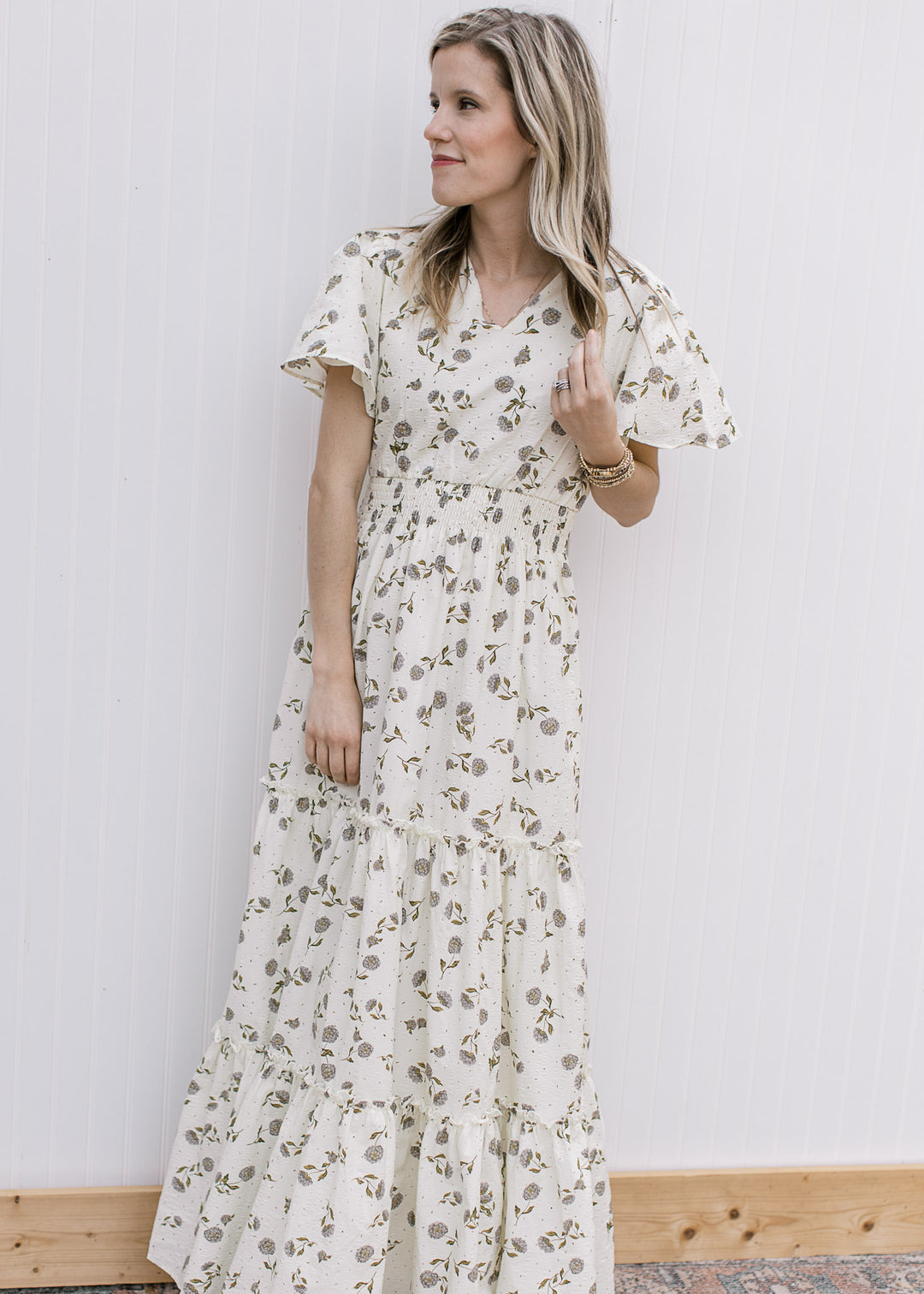 Model wearing a cream v-neck maxi with hydrangea print, flutter short sleeves and elastic waist.