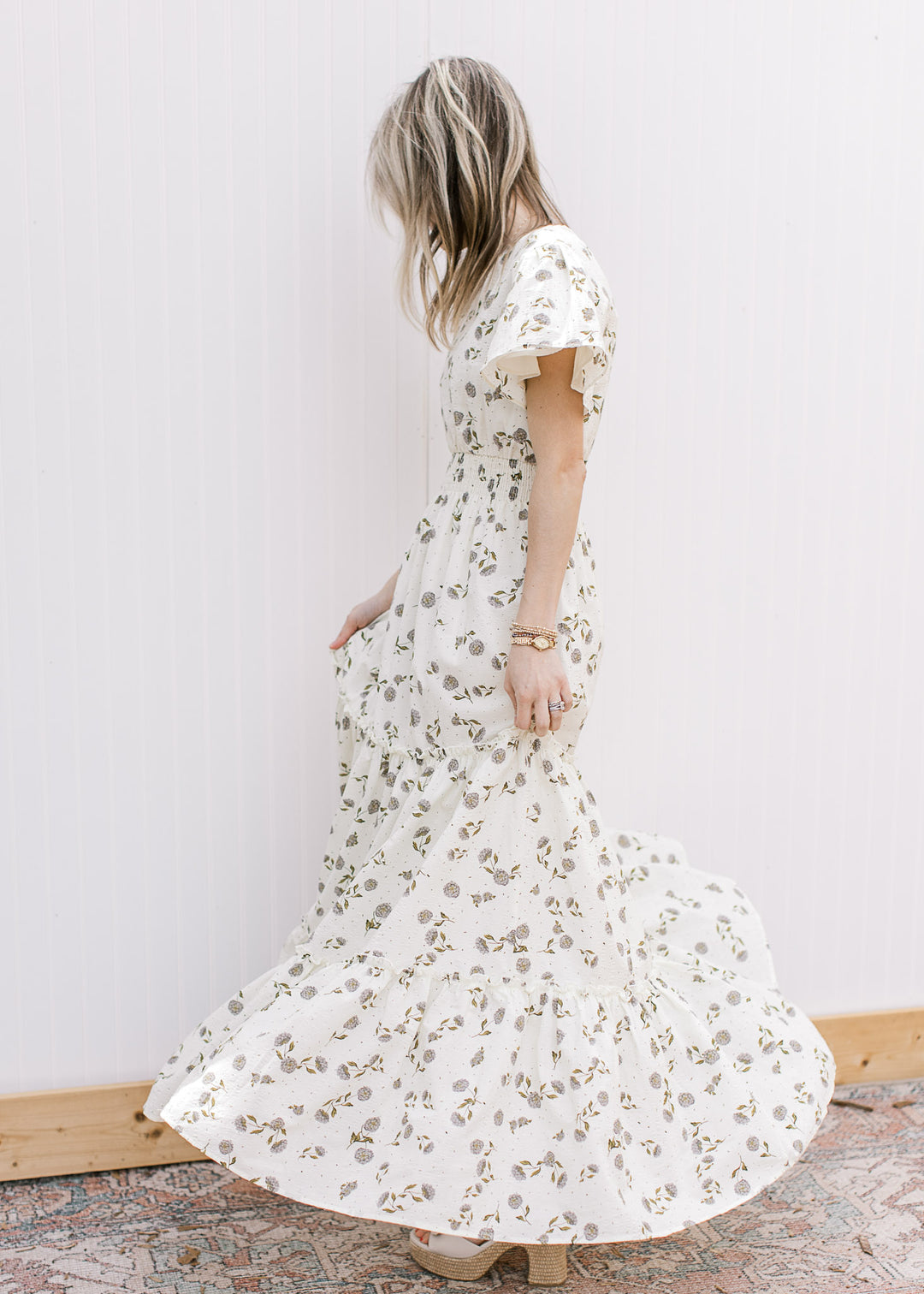 Side view of model spinning in a cream maxi with hydrangea print, short sleeves and elastic waist.