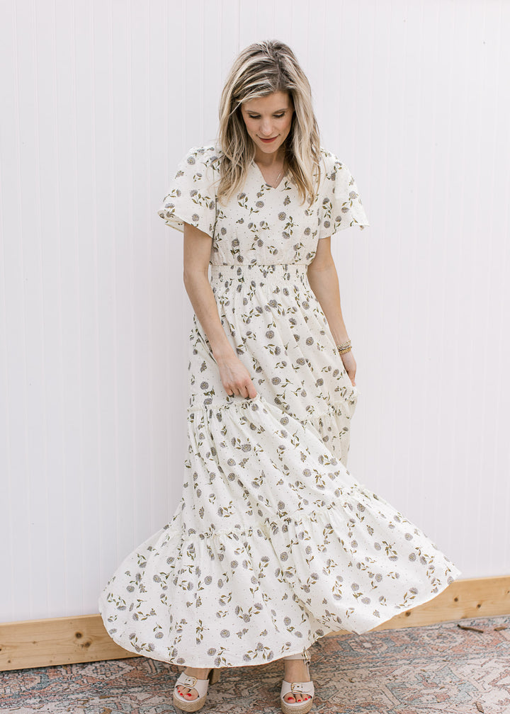 Model twirling in a cream v-neck maxi with hydrangea print, flutter short sleeves and elastic waist.