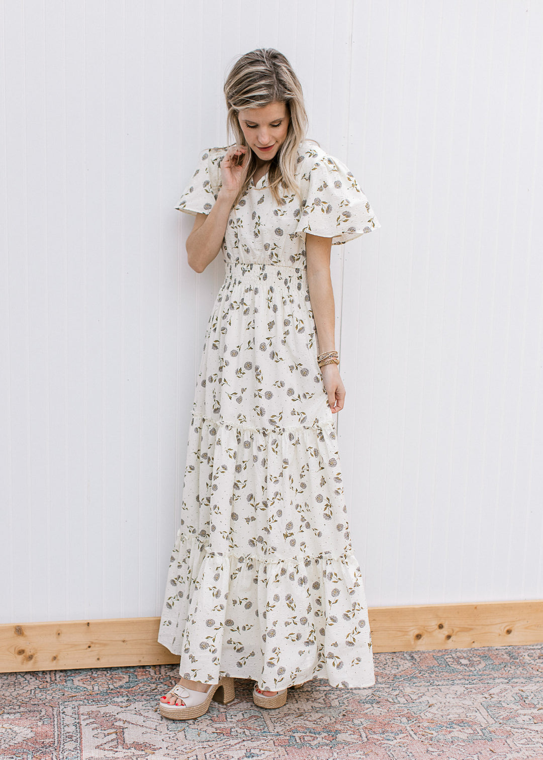 Side view of Model wearing a cream maxi with hydrangea print, short sleeves and elastic waist.