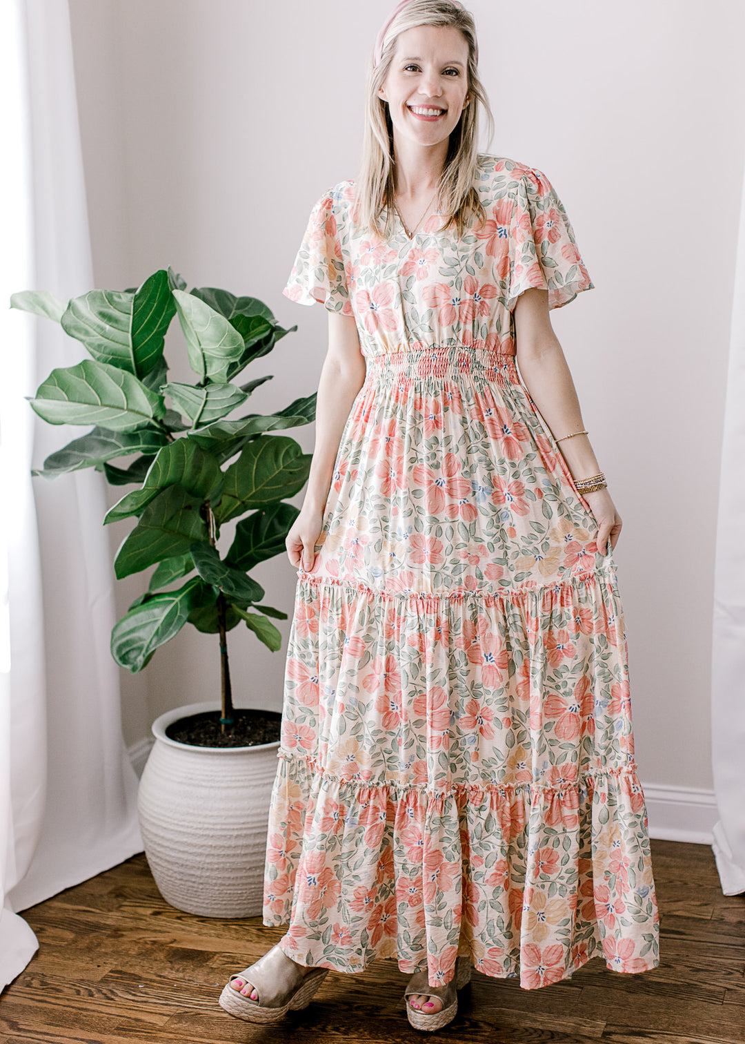 Model wearing a beige maxi with floral, short sleeves, v-neck, tiered skirt and elastic waist.