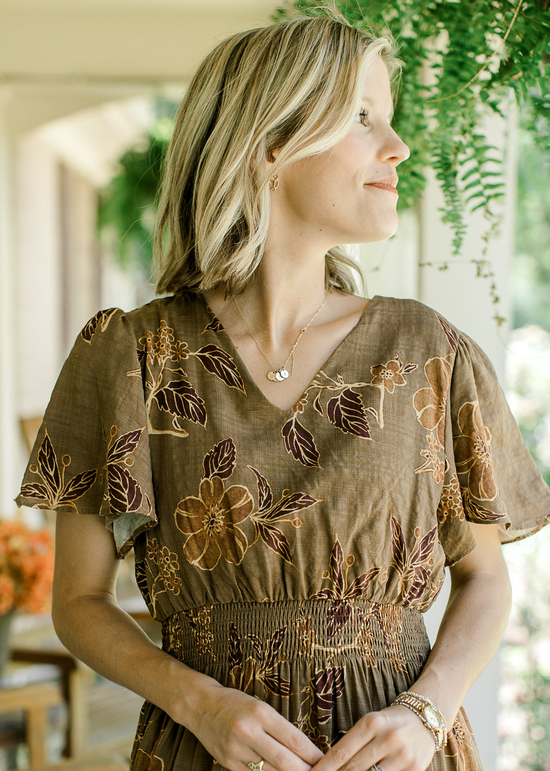 Close up of neckline of blonde model wearing floral maxi with gold, brown, and rust pattern.
