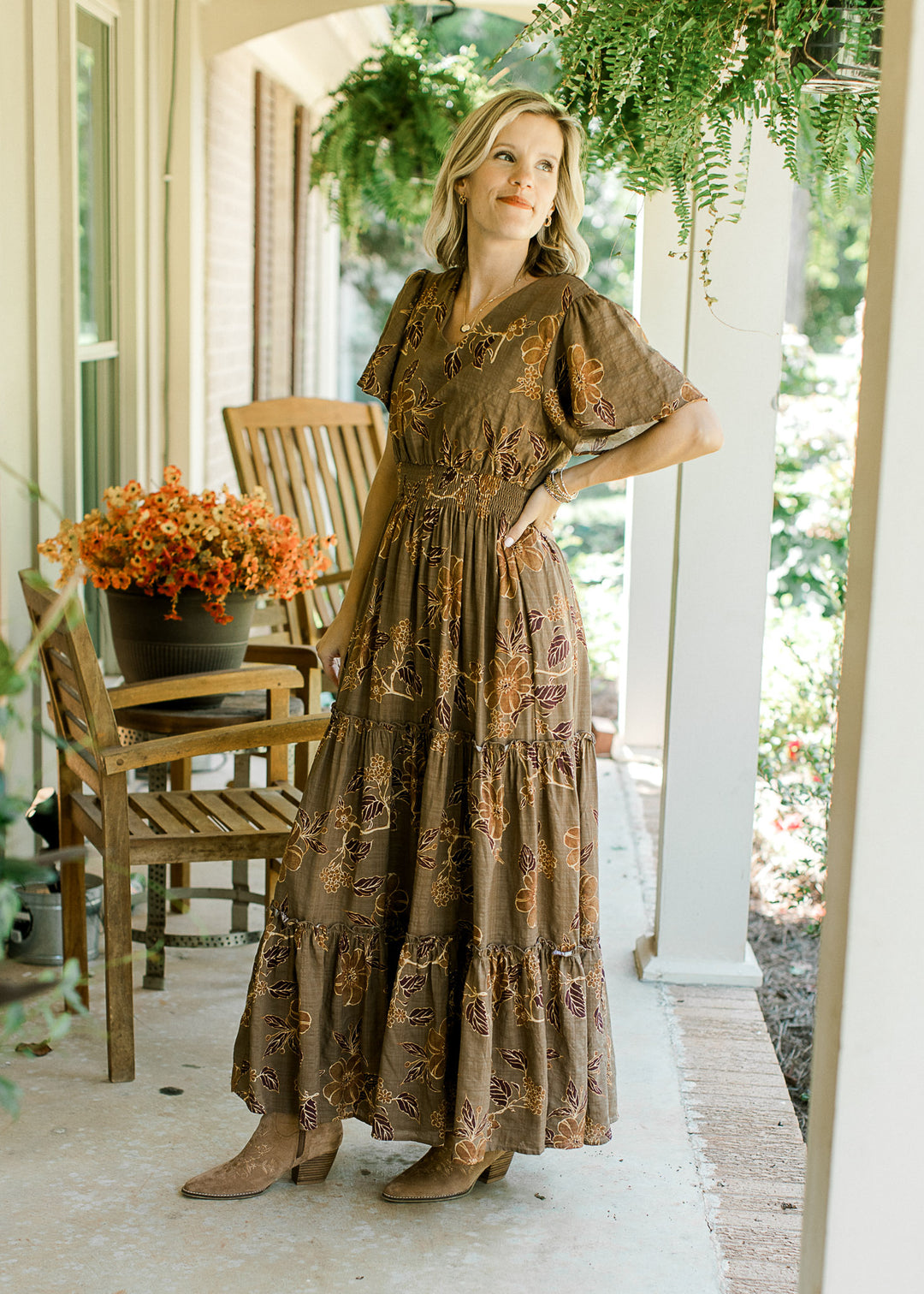 Blonde model wearing floral maxi with gold, brown, and rust pattern.