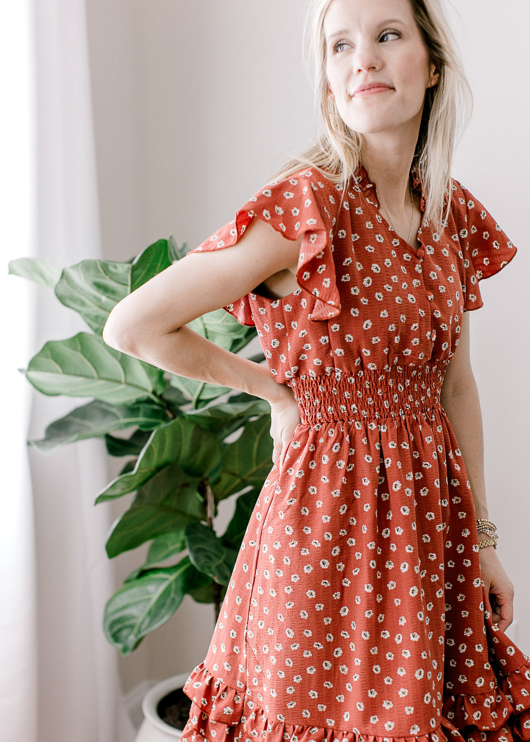Close up of ruffle cap sleeve and smocked waistband on a maroon dress with white floral. 