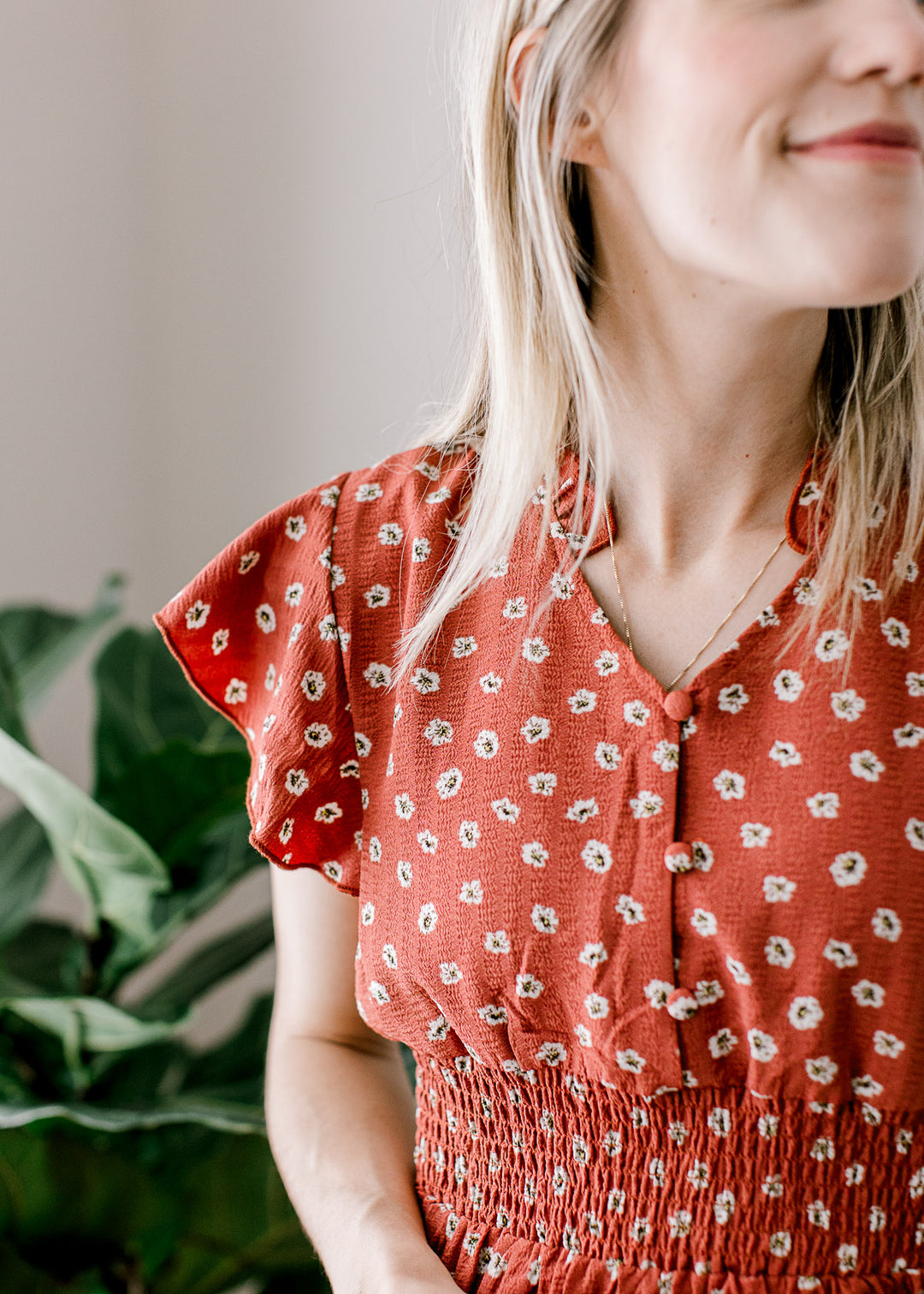 Close up of three buttons v-neck of a maroon dress with ruffle cap sleeves and a smocked waist.