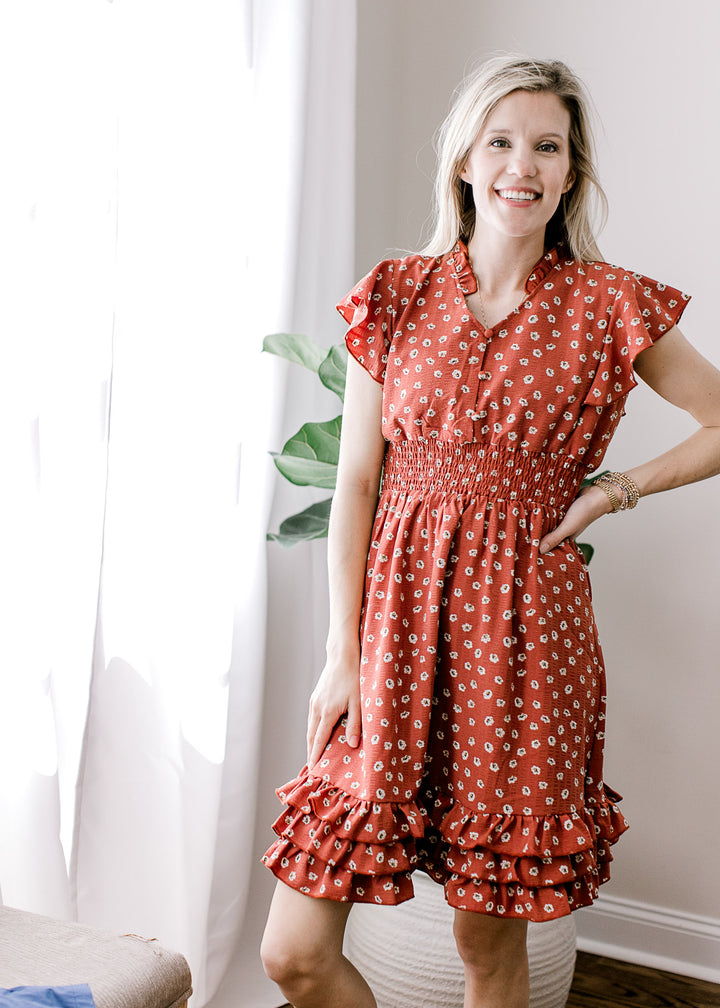 Model wearing a maroon dress with white floral, v-neck with a ruffle and a smocked waistband.