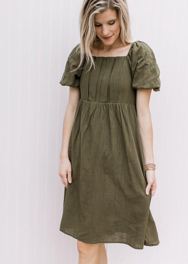 Model wearing a textured olive knee length dress with a square neck and bubble short sleeves.