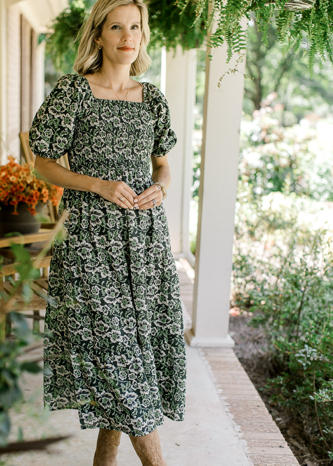 Model wearing an indigo midi with cream and green floral, square neck and smocked bodice. 
