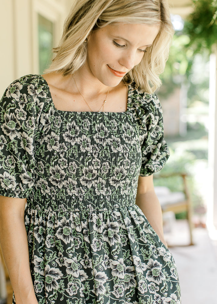 Close up of square neck, smocked bodice and bubble short sleeves on an indigo midi with floral. 
