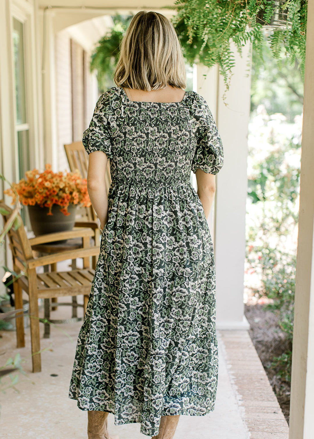 Back view of Model in an indigo midi with cream and green floral, square neck and short sleeves.