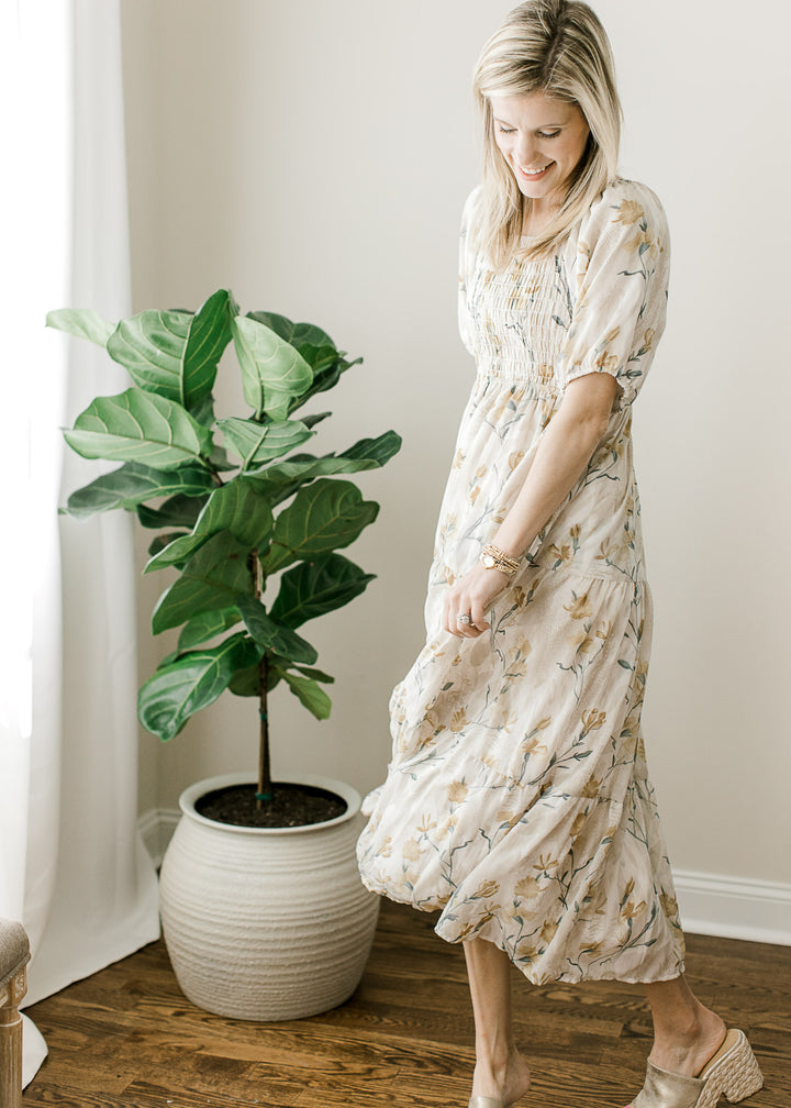 Model wearing a cream short sleeve midi with floral, short sleeves, square neck and smocked bodice. 