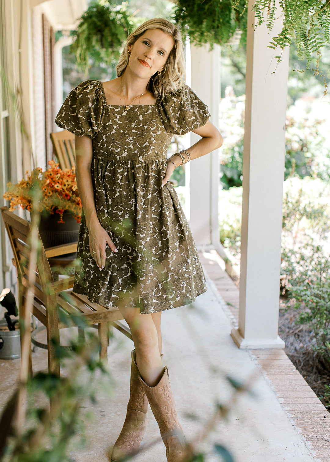 Model wearing a khaki dress with brown floral, square neck, bubble short sleeves and elastic waist.