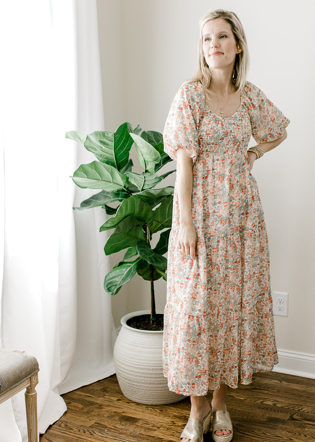 Model wearing an off white midi with peach, green, and yellow floral and bubble short sleeves. 
