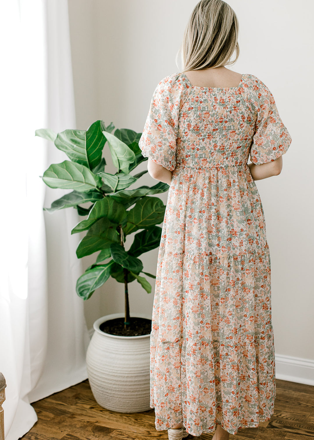 Back view of off white midi with floral, a tiered skirt, square neck and smocked bodice. 