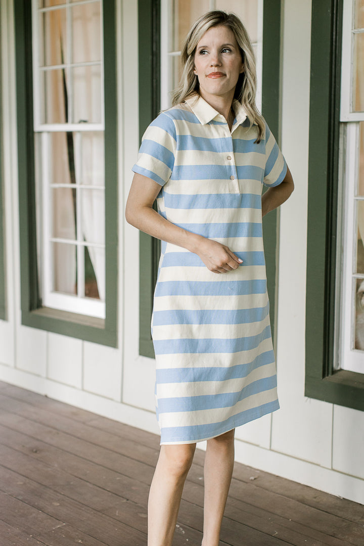 Model wearing a pale yellow and blue striped knee length dress with a collar and short sleeves. 