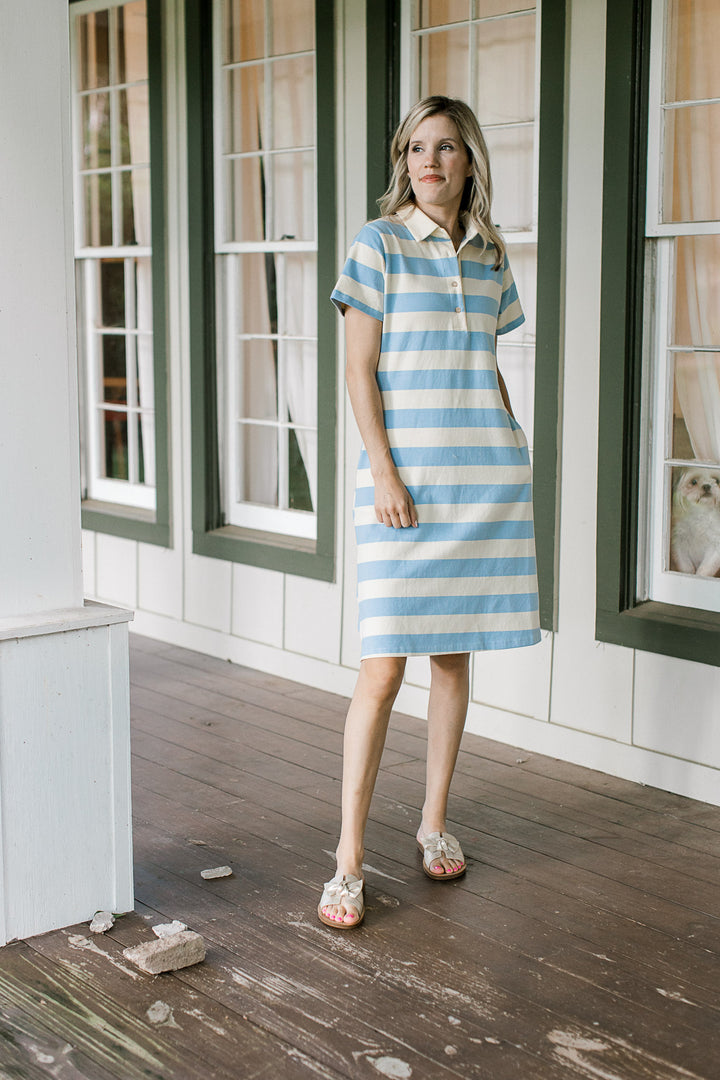 Model wearing sandals and a pale yellow and blue striped dress with a collar and short sleeves.