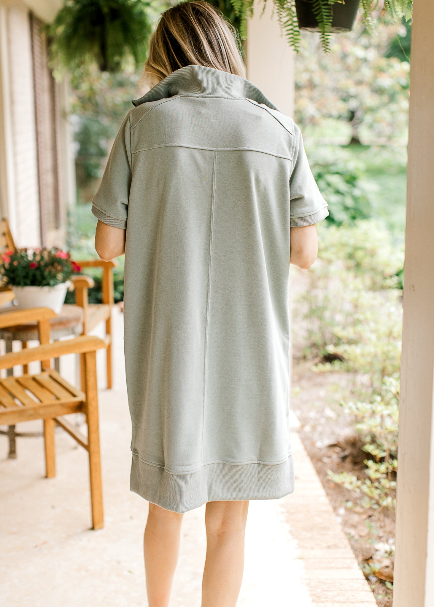 Back view of Model wearing a mossy green dress with short sleeves and a mock neck. 
