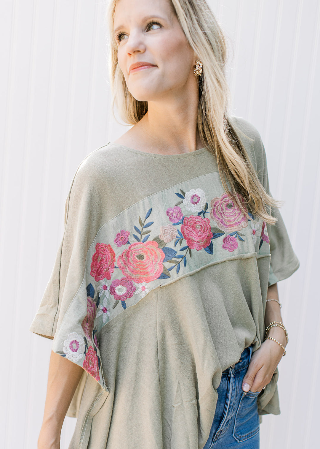 Close up of extended shoulder on a sage top with floral design across the bust. 
