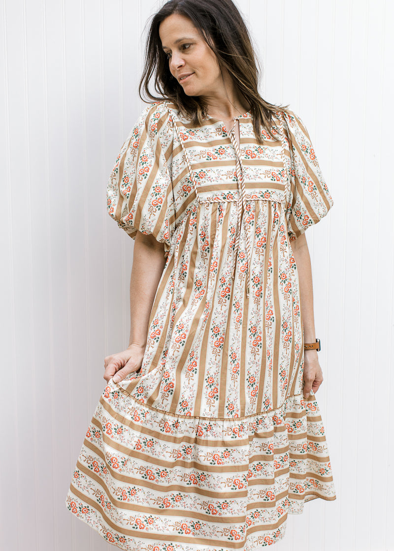 Model wearing a cream midi with golden stripes, bubble short sleeves and v-neck with tie.