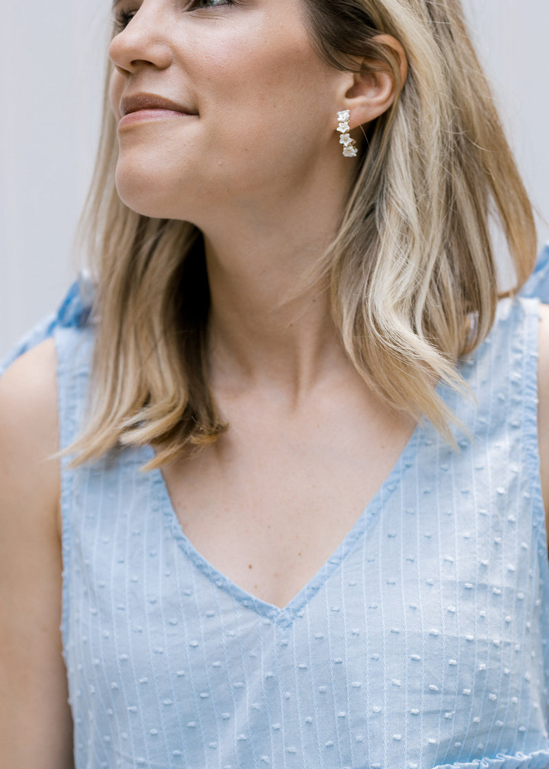 Model wearing hoop earrings with a white pearl flower design. 