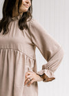 Close up of poet long sleeve on a beige babydoll top and a round neck with a ruffle. 