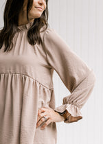 Close up of poet long sleeve on a beige babydoll top and a round neck with a ruffle. 