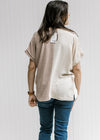 Back view of Model wearing a cream and tan two-toned v-neck top with short sleeves. 