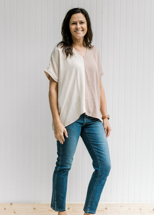Model wearing a cream and tan two-toned v-neck top with short sleeves. 