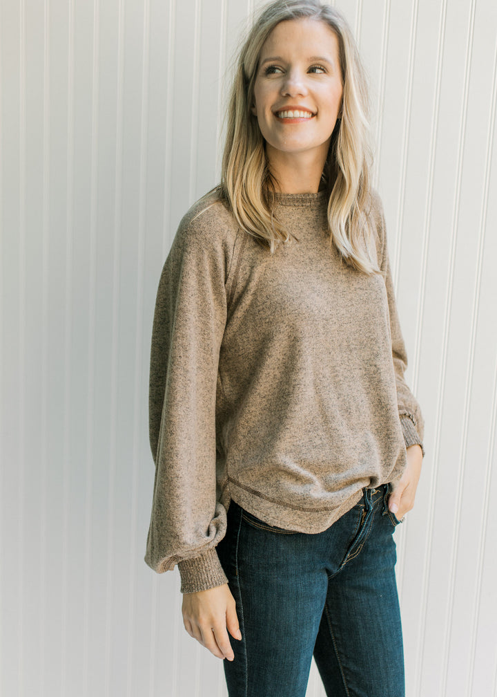 Model wearing a light brown top with a round neck, long sleeves and ribbing at the cuff and neck. 