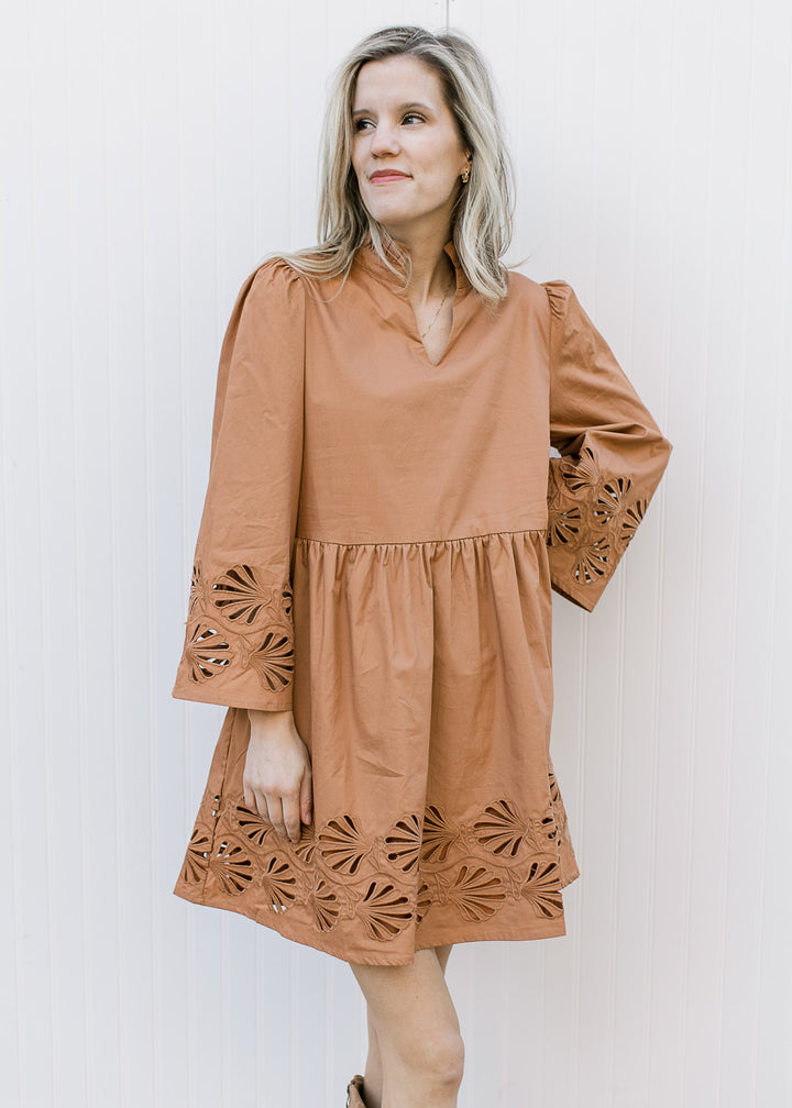 Model wearing a toffee babydoll dress with a floral lace cutout at cuff and hem and 3/4 sleeves.