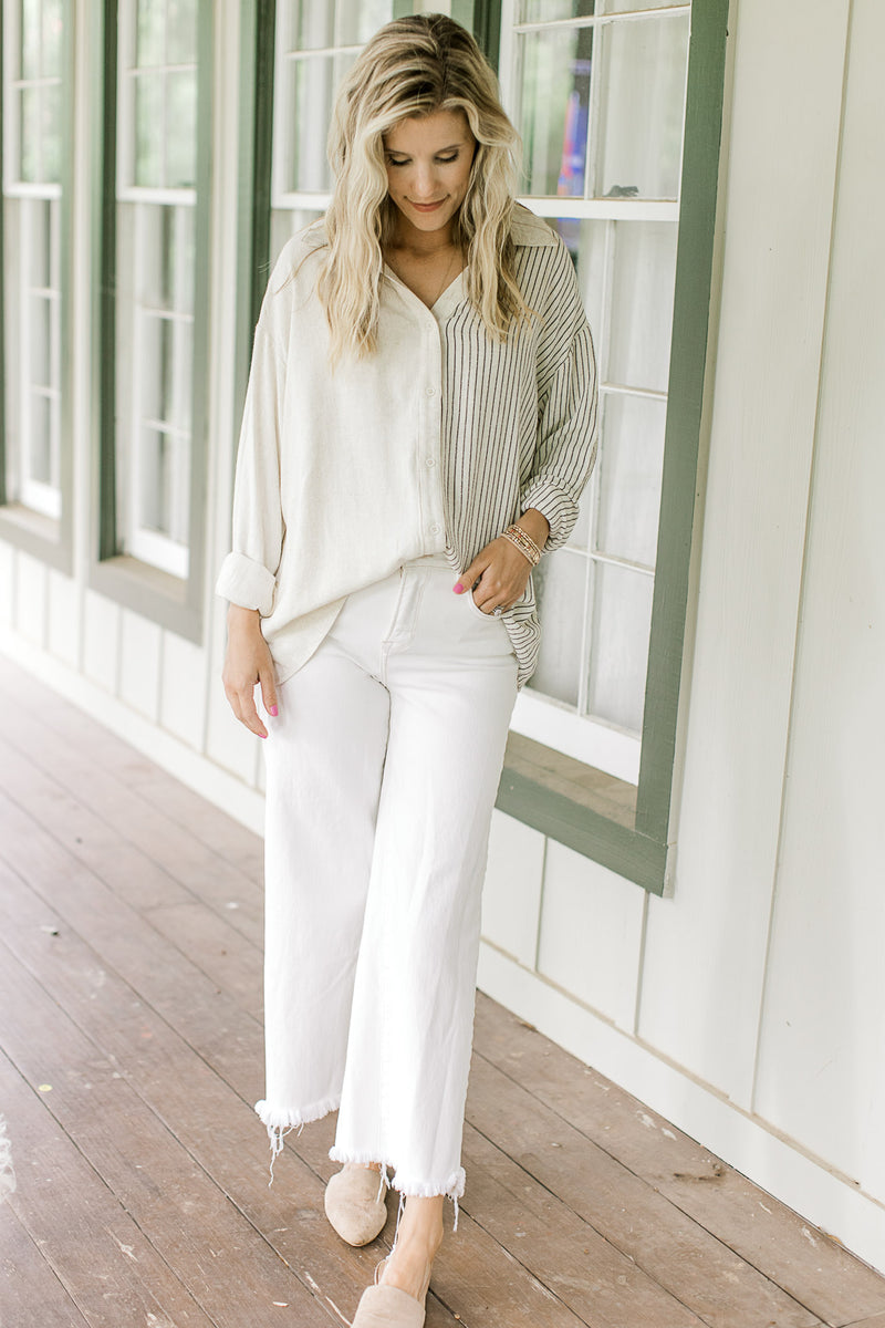 Model wearing a long sleeve button down top with one side cream and one side navy stripes.