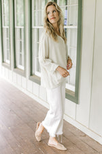 Model wearing white pants with a button down top with one side cream and one side navy stripes.