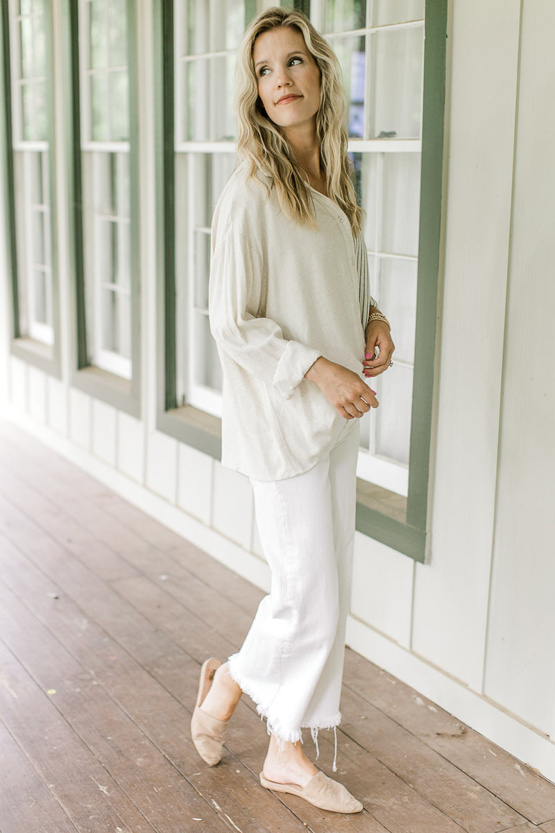 Model wearing white pants with a button down top with one side cream and one side navy stripes.