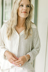 Model wearing a button down top with one side cream and one side navy stripes.