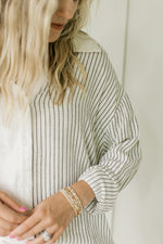 Close up of blue pin stripes and buttons on a cream and blue striped top with long sleeves.