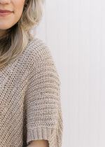 Close up of extended shoulder short sleeve on a knit taupe sweater with a v-neck.
