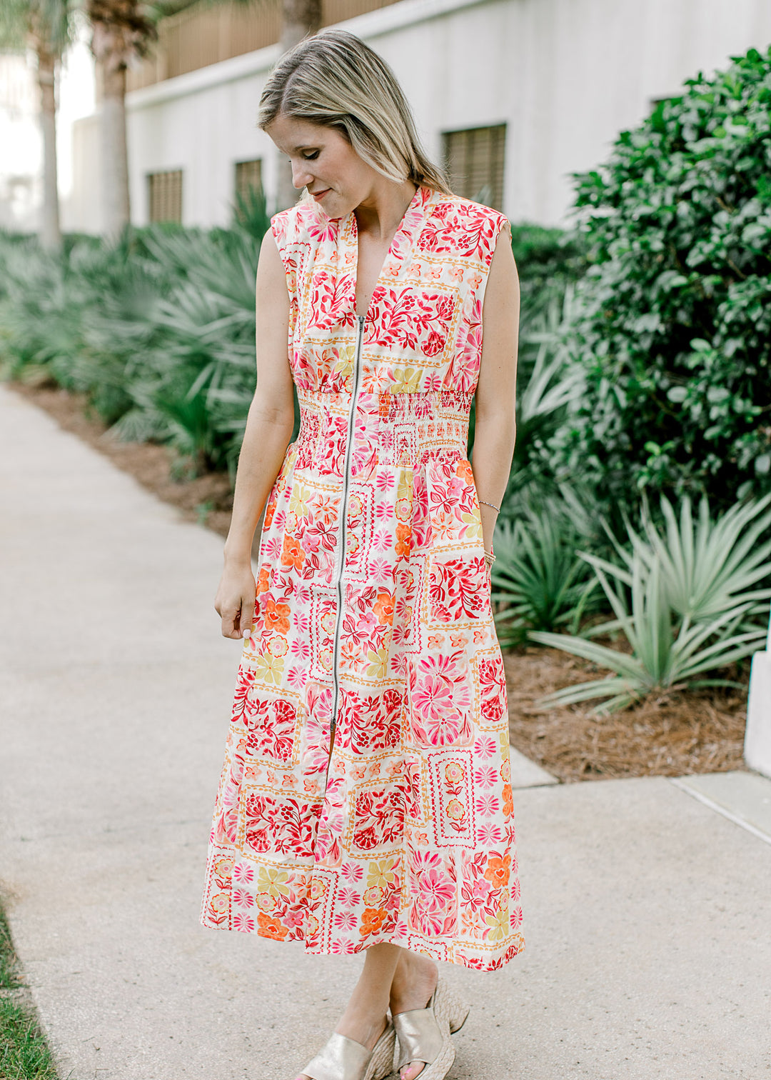 Model wearing an off white midi with bright floral, v-neck, front zipper and shoulder pads.