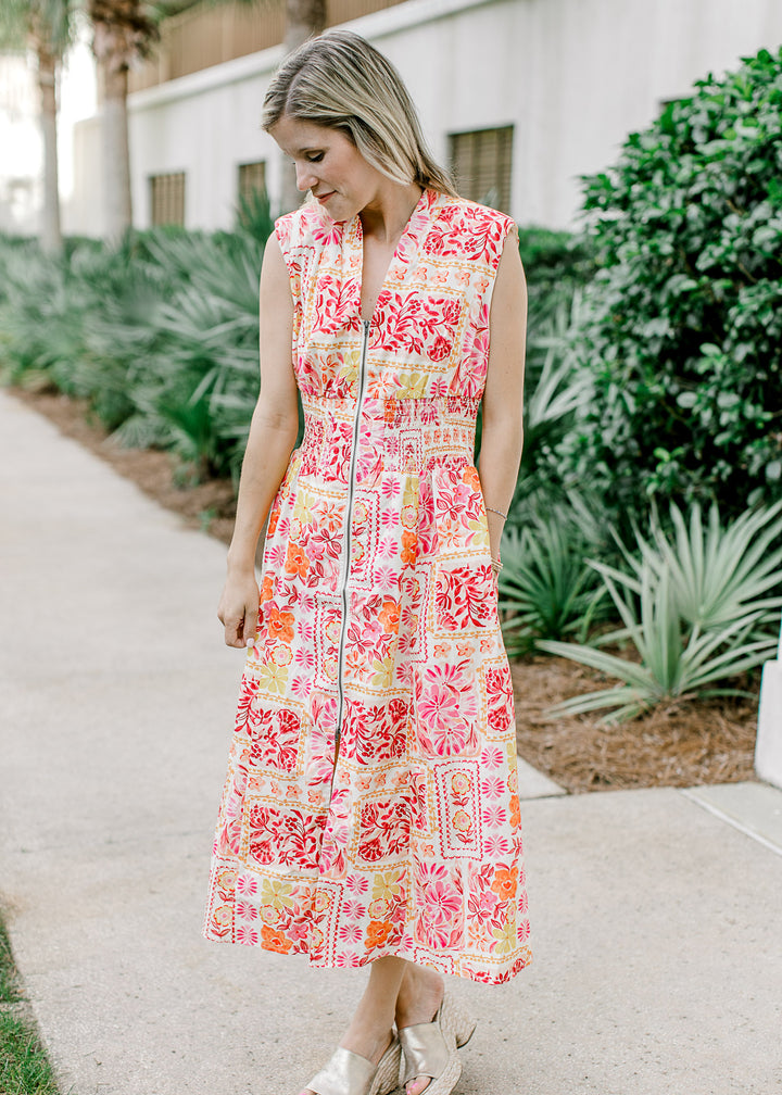 Model wearing an off white midi with bright floral, v-neck, front zipper and shoulder pads.