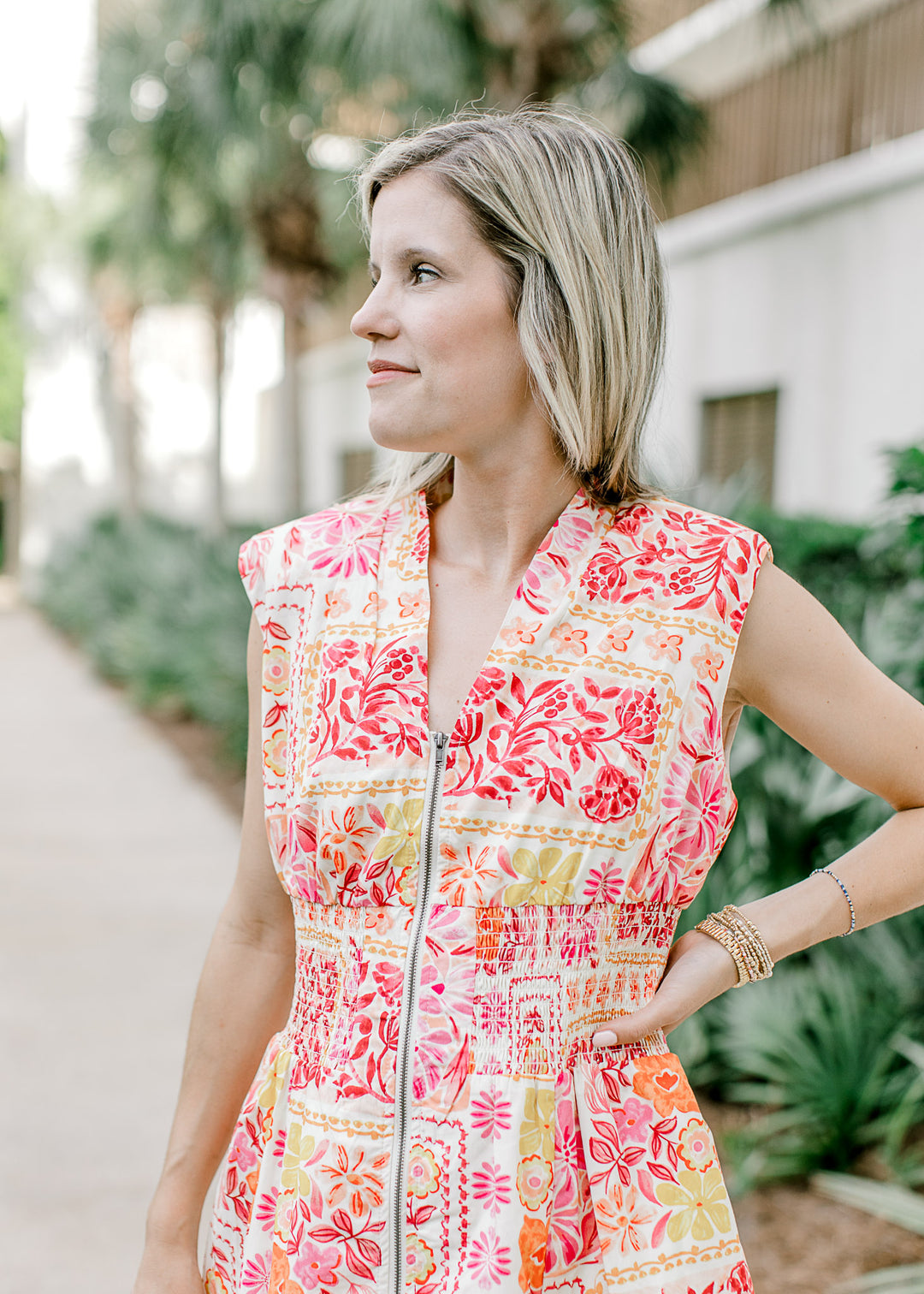Close up of smocked waist and v-neck on a cream midi with bright floral and a zipper closure. 