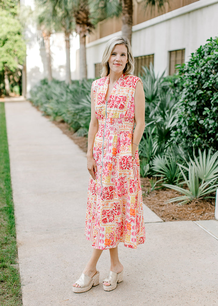 Model wearing heels and an off white midi with bright floral, v-neck, zipper and shoulder pads.
