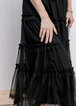 Close up of tiers on the tulle overlay of a black midi skirt with an elastic waist. 