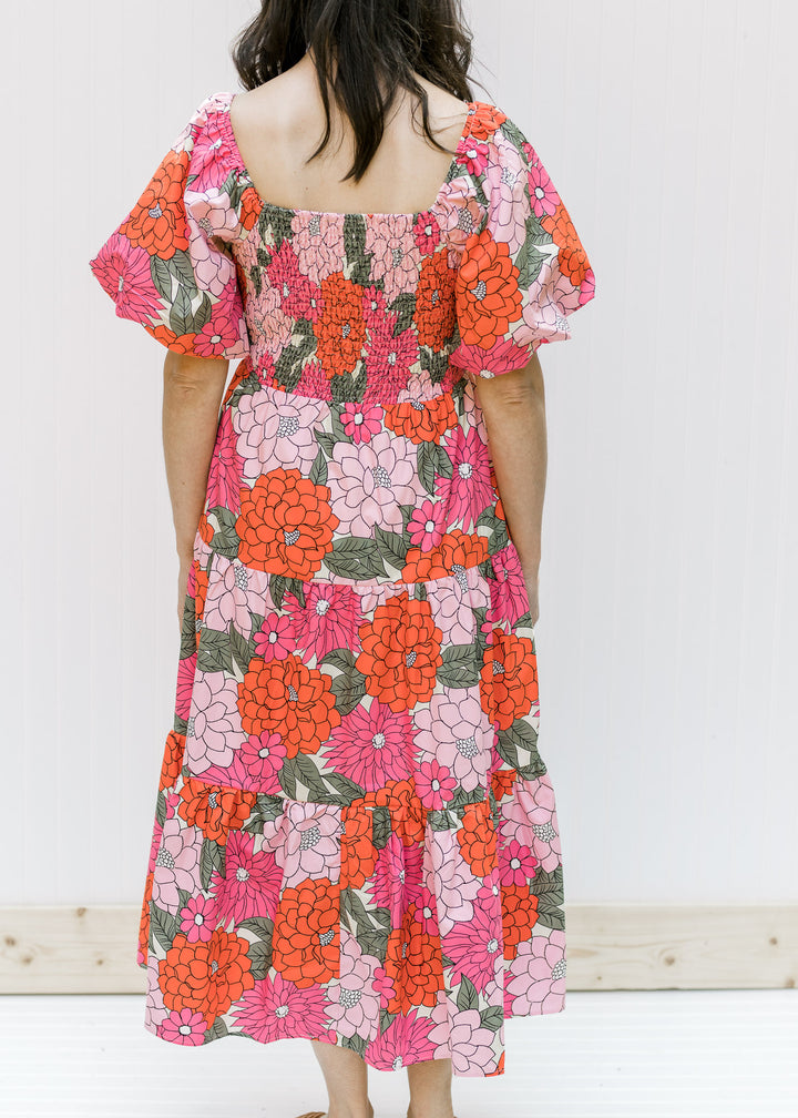 Back view of Model wearing a coral midi dress with a square neck, smocked back and short sleeves. 