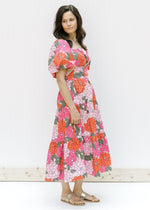 Model wearing sandals with a coral floral midi dress with a square neck and short puff sleeves. 