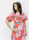 Model wearing a coral floral midi dress with pockets, a square neck and puff short sleeves. 